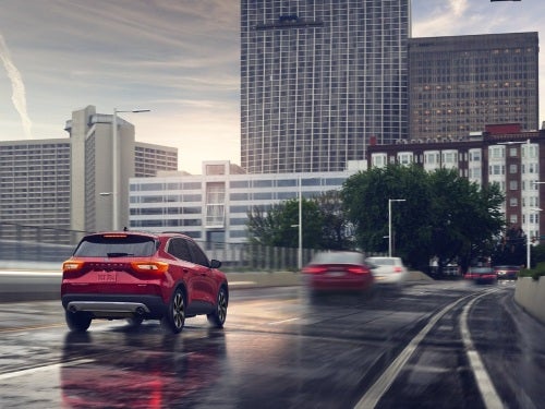 2024 Ford Escape driving into a city on a wet road