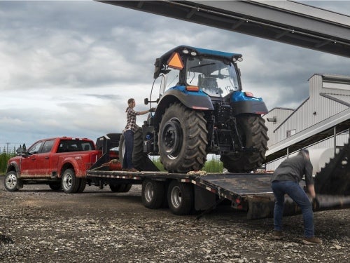2024 Ford Super Duty towing a trailer with a large tractor on it